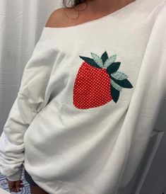 a woman wearing a white shirt with a red strawberry on it