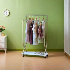 an ironing board with clothes hanging on it in front of a green painted wall