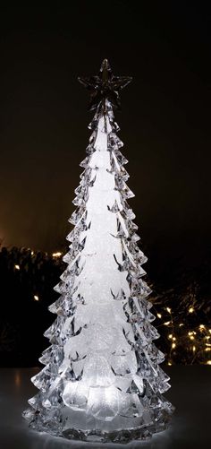 a glass christmas tree with lights in the background