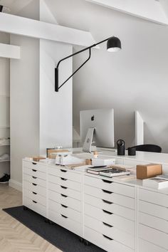 an office with white drawers and black lighting