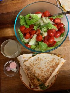 a salad with tomatoes, lettuce and cucumber in a glass bowl