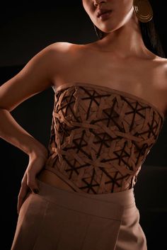 Strapless bodice top combining the classic sophistication of bustier-inspired seams and form-fitting top stitching finish this exquisite geometric weaved corset in shades of brown. The suede semi-sheer top features a bandeau neckline and is crafted entirely in a diamond weave pattern. More structure has been added with the help of boning on the front and back. Pair this stunning piece with high-waist faux leather pants and pumps to stimulate the overall appearance.Model wears a size small / Bust Formal Suits For Women, Oversized Wool Coat, Sheer Pants, Form Fitting Tops, Pleated Jumpsuit, Bodice Top, Diamond Weave, Backless Top, Weave Pattern