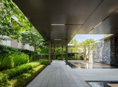 the walkway is lined with green plants and water features on both sides, as well as an outdoor fountain