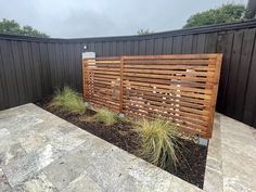 a wooden fence in the middle of a stone patio with grass growing on top of it