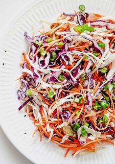 a white plate topped with coleslaw slaw and carrots on top of a table