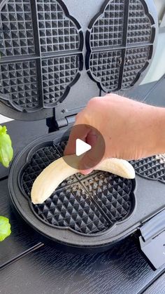 a person holding a banana over some waffles