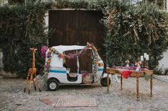 a small car decorated with flowers and giraffes is parked in front of a building