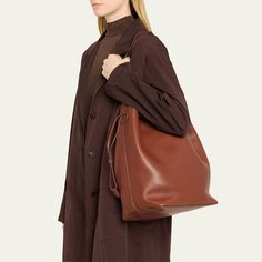 THE ROW "Belvedere" bucket bag in saddle leather  Shoulder strap  Drawstring closure  Interior, one zip pocket  Approx. 7.1"H x 14.8"W x 11.8"D Made in Italy Brown Bag, Saddle Leather, Brown Bags, Bucket Bag, Saddle, The Row, Zip Pockets, Shoulder Strap, Tops Designs