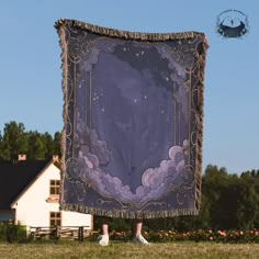 a woman standing in front of a purple and black blanket with clouds on it,