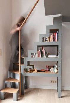 there is a man climbing up the stairs in this room with bookshelves and shelves