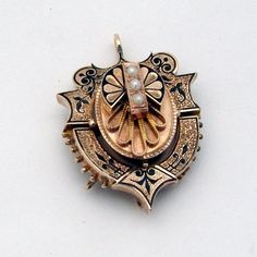 "Victorian era ornate 14 K (.585) rose gold locket pendant, decorated with Seed Pearls and black enamel. It was a combination of brooch and pendant, but the pin was removed (in current condition it is a pendant). This magnificent antique locket is 1 1/2\" long, 1 1/8\" wide and weighs 12.3 grams. The pendant is slightly bent, and there is some enamel loss  due to age. EA2188" Ornate Engraved Brooch, Engraved Yellow Gold Pendant Brooch, Victorian Locket Pendant Brooches, Victorian Brooches With Locket Pendant, Gold Locket-shaped Brooch, Ornate Gold Locket Brooches, Gold Pendant Locket Brooch, Gold Pendant Locket Brooches, Gold Locket Pendant Brooches