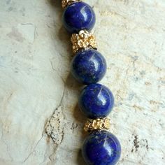 "This is a stunning Lapis Lazuli beaded necklace. The deep blue colour is accompanied by gold plated floral spacer beads. The spacers add an added touch of gold colour to complement the Lapis. Small flecks of gold are found throughout the stone beads and add to it's unique one of a kind nature. The clasp in the back is also gold plated and very easy to use. A great statement piece for both daytime and evening. Dimensions: Length - 17.75 \" Approximate diameter of stones: 1.2 cm extender- an exte Luxury Blue Gemstone Bead Necklaces, Luxury Blue Beaded Necklaces With Gemstone Beads, Luxury Blue Gemstone Beaded Necklaces, Luxury Blue Beaded Necklace With Polished Beads, Luxury Blue Gemstone Beaded Necklace, Luxury Blue Polished Beads Necklace, Elegant Hand-strung Blue Beaded Necklaces, Elegant Blue Hand-strung Beaded Necklaces, Luxury Blue Beaded Necklace For Gift