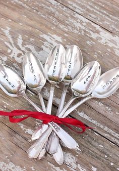 six spoons tied together with a red ribbon on top of an old wooden table