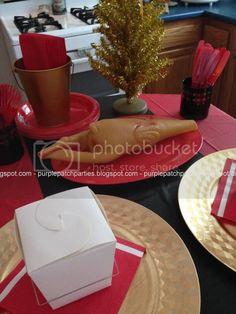 the table is set for christmas dinner with red napkins and gold placemats