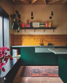 a kitchen with green cabinets and yellow tile backsplashing, bookshelves above the sink