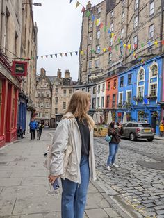 a woman walking down a street next to tall buildings