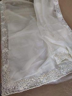 This is a fascinating pure organza silk saree in gorgeous white color, monochrome look. Saree features a dazzling beads and pearl work embroidery of floral design throughout the edges of the saree. Simple pearl work is twinkling all over the body of the saree. The beads and pearl embroidery are delicately hand embellished. Organza is a lightweight plain weave fabric. The pure organza attributes to a very comfy and flowy drape. Organza is considered as one of the most stylish and glamorous wear. Elegant White Chikankari Embroidery Blouse Piece, Elegant Off White Blouse With Resham Embroidery, Semi-stitched White Organza Saree, Elegant Off White Blouse With Chikankari Embroidery, Festive Off White Organza Saree, Off White Silk Saree For Wedding, Elegant White Blouse With Cutdana Details, Elegant White Blouse With Cutdana, Elegant White Blouse Piece With Cutdana