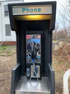 an old style phone booth sitting in front of a house