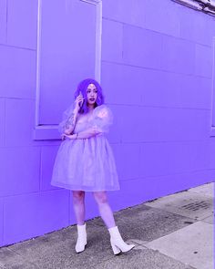 a woman with purple hair is standing in front of a purple wall