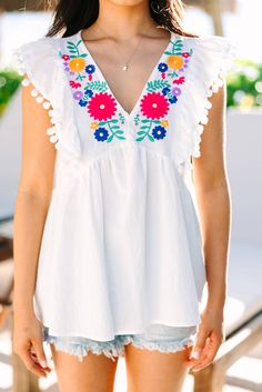 White Floral Embroidered Pompom Flutter Blouse Summer V-neck Tops With Tassels, Summer V-neck Top With Tassels, Summer V-neck Blouse With Floral Embroidery, Sleeveless Embroidered Tops For Brunch, Summer V-neck Top With Geometric Embroidery, Chic Embroidered Tops For Vacation, Multicolor Embroidered V-neck Top For Vacation, White Embroidered Top For Summer Brunch, Spring Vacation Embroidered Top With Embroidered Neckline