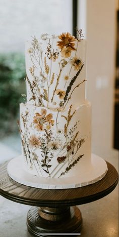 a three tiered white cake with dried flowers on it