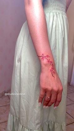 a woman's hand with a pink flower tattoo on her left arm and wrist