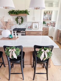 two chairs with bows on them sit in front of a kitchen island decorated for christmas