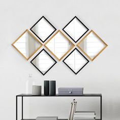 three mirrors mounted to the side of a wall next to a table with a vase on it