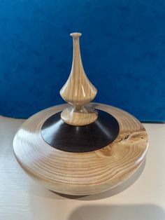 a wooden object sitting on top of a white table next to a blue wall in the background