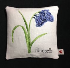 a white pillow with bluebells embroidered on it