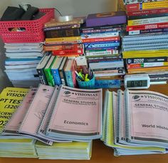 a pile of books sitting on top of a wooden table next to a calculator