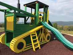 a green and yellow play structure with a slide