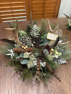 the centerpiece is decorated with antlers, pine cones and greenery on a wooden table