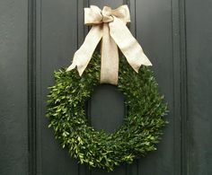 a green door with a white bow on it and a wreath hanging from the front