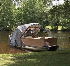 a boat with a shark's mouth on it is in the water near some trees