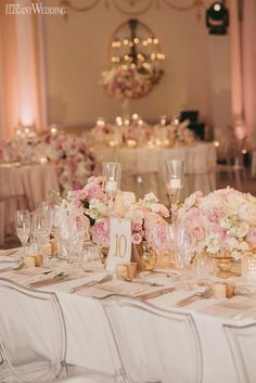 the table is set with pink and white flowers, gold rimmed glasses, and candles