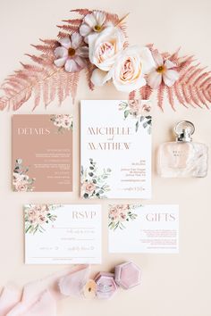 the wedding stationery is laid out with flowers and greenery