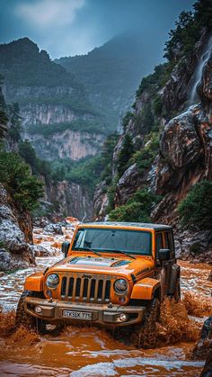 an orange jeep driving through some muddy water