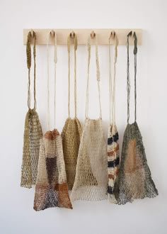 five bags hanging from a wooden hook on a wall