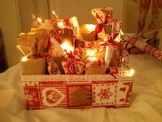 a box filled with wrapped presents on top of a bed