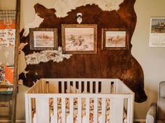 a baby crib in front of a cow skin wall with pictures on the wall