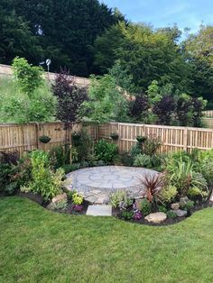 a garden with lots of different types of plants and trees in it, along with a fence