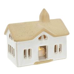 a small white house with a candle in it's window and light coming out