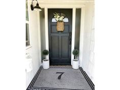 the front door is decorated with two planters and a number seven sign on it