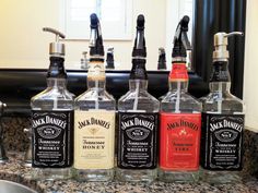 six bottles of jack daniels are lined up on the counter in front of a mirror