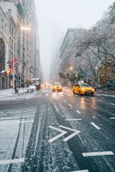 two taxi cabs driving down a snow covered street