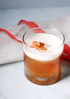 a glass filled with liquid sitting on top of a white table next to a red bag