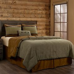 a bed in a bedroom with wooden walls and flooring next to a large window