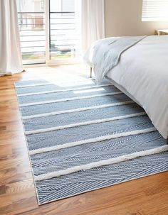 a white bed sitting on top of a hard wood floor next to a wooden door