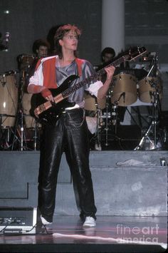 a man standing on top of a stage holding a guitar